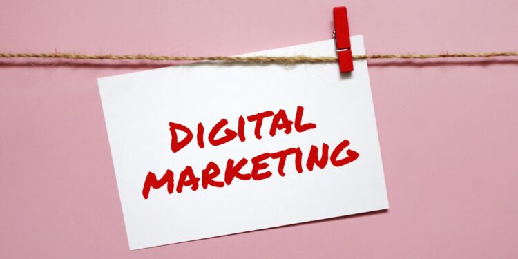 Sticker with the inscription digital marketing hanging on a rope on a pink background