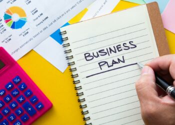 Business plan written on notepad with graph analysis background. Business Plan Concept