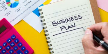 Business plan written on notepad with graph analysis background. Business Plan Concept