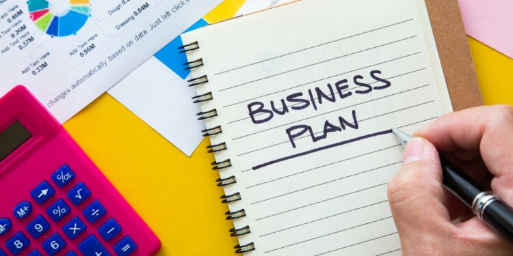 Business plan written on notepad with graph analysis background. Business Plan Concept